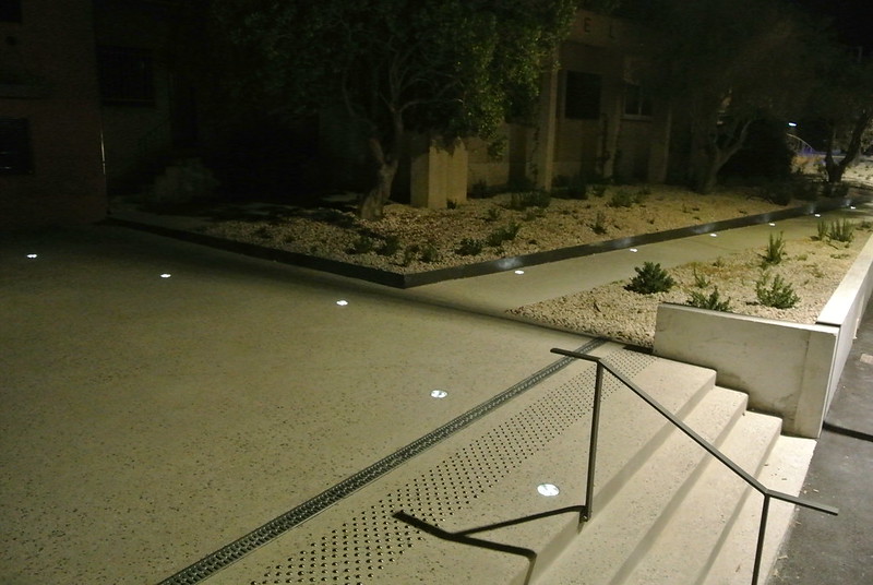 Solar-powered in-ground crystal studs lighting a pedestrian pathway at night, enhancing safety and visibility with subtle, off-grid illumination.