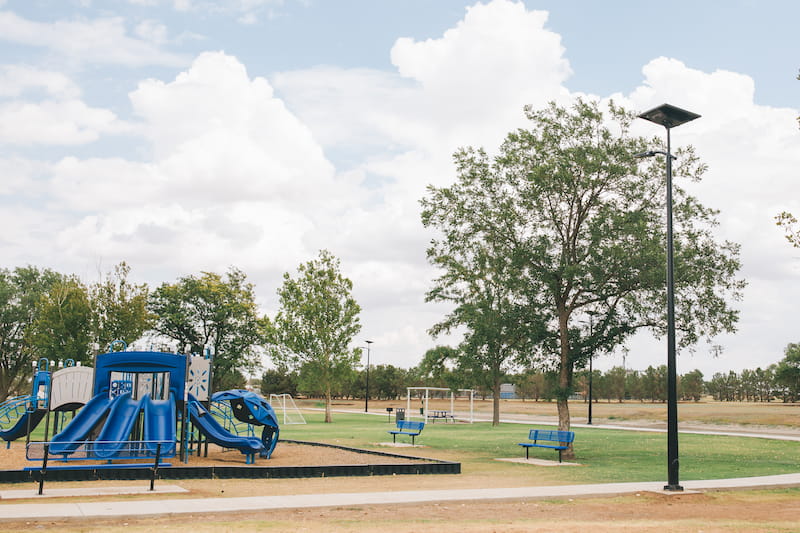 Solar lighting system illuminating a playground in a city park, providing safety after dark.