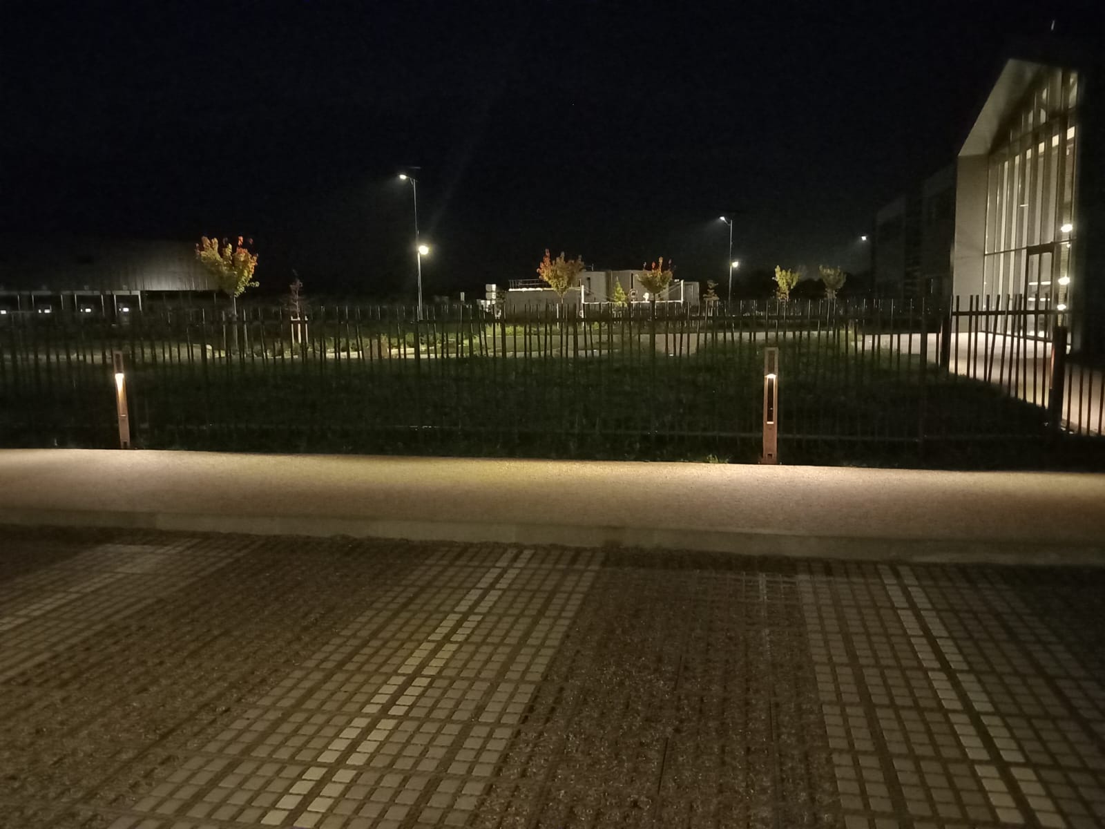 Solar bollard lights illuminating a building parking lot at night, providing safe and sustainable off-grid lighting for commercial spaces.