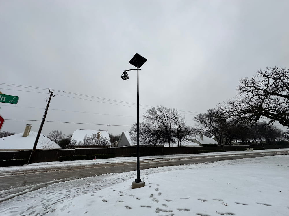 SmartLight solar streetlight illuminating a snow-covered residential area during winter.