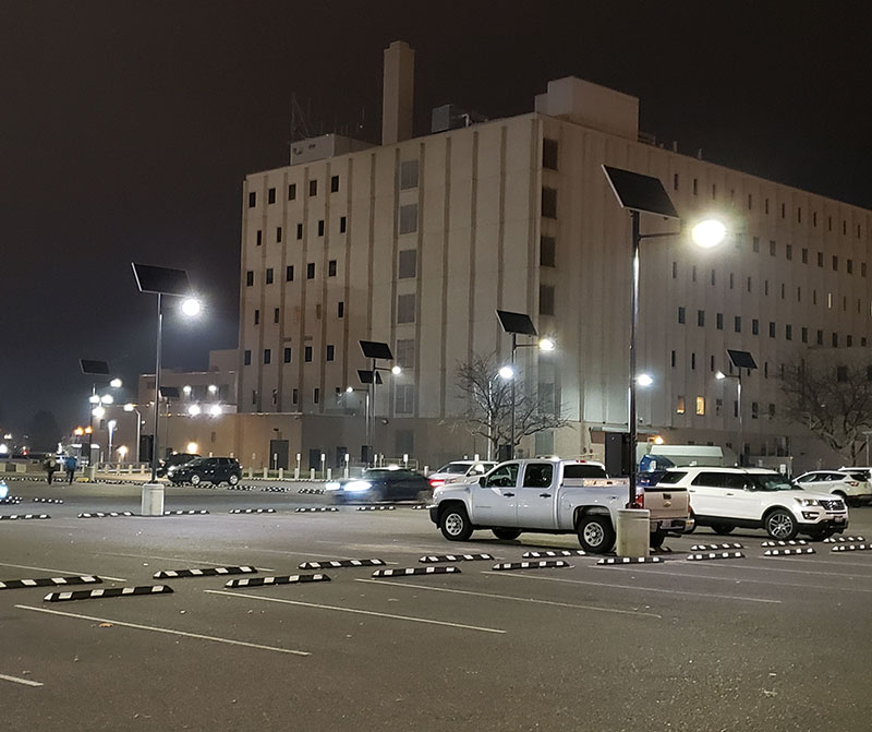 Solar streetlights installed at a military facility, providing off-grid security lighting for high-priority areas. Autonomous solar street lights illuminating a military or federal facility parking area at night, providing secure, resilient outdoor lighting for government and defense applications.