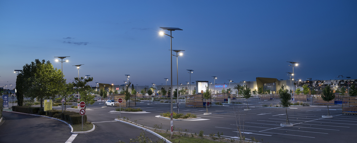 Solar-powered parking lot lights for retail spaces, offering efficient lighting and enhanced security. Solar lighting illuminating a retail shopping center parking lot at dusk