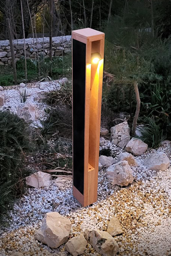 Solar bollard light installed in a landscaped garden area providing sustainable pathway illumination.