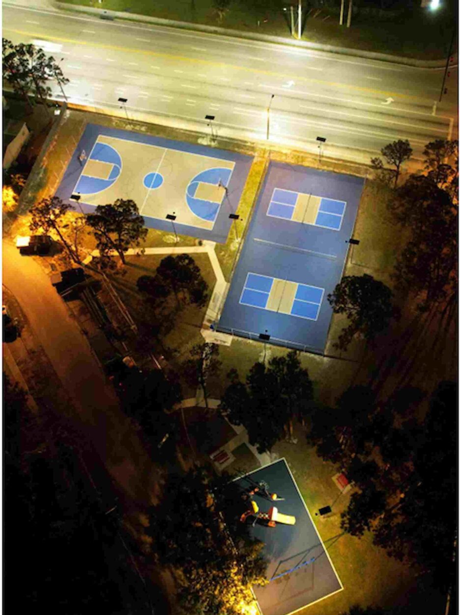 Aerial night view of outdoor basketball courts illuminated by solar streetlights, creating a safe and vibrant community recreation space.