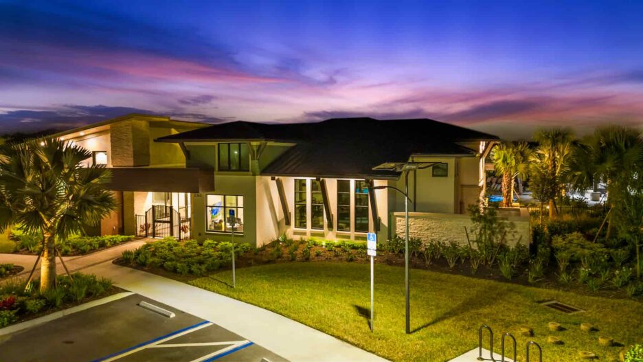 Solar-powered SmartLight illuminating a Florida community building and landscaped pathway at dusk, with accessible parking and palm trees in view.
