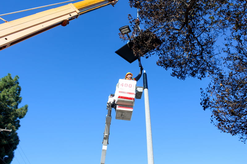 Los Angeles technician installing a solar streetlight, demonstrating efficient, trench-free deployment under clear skies