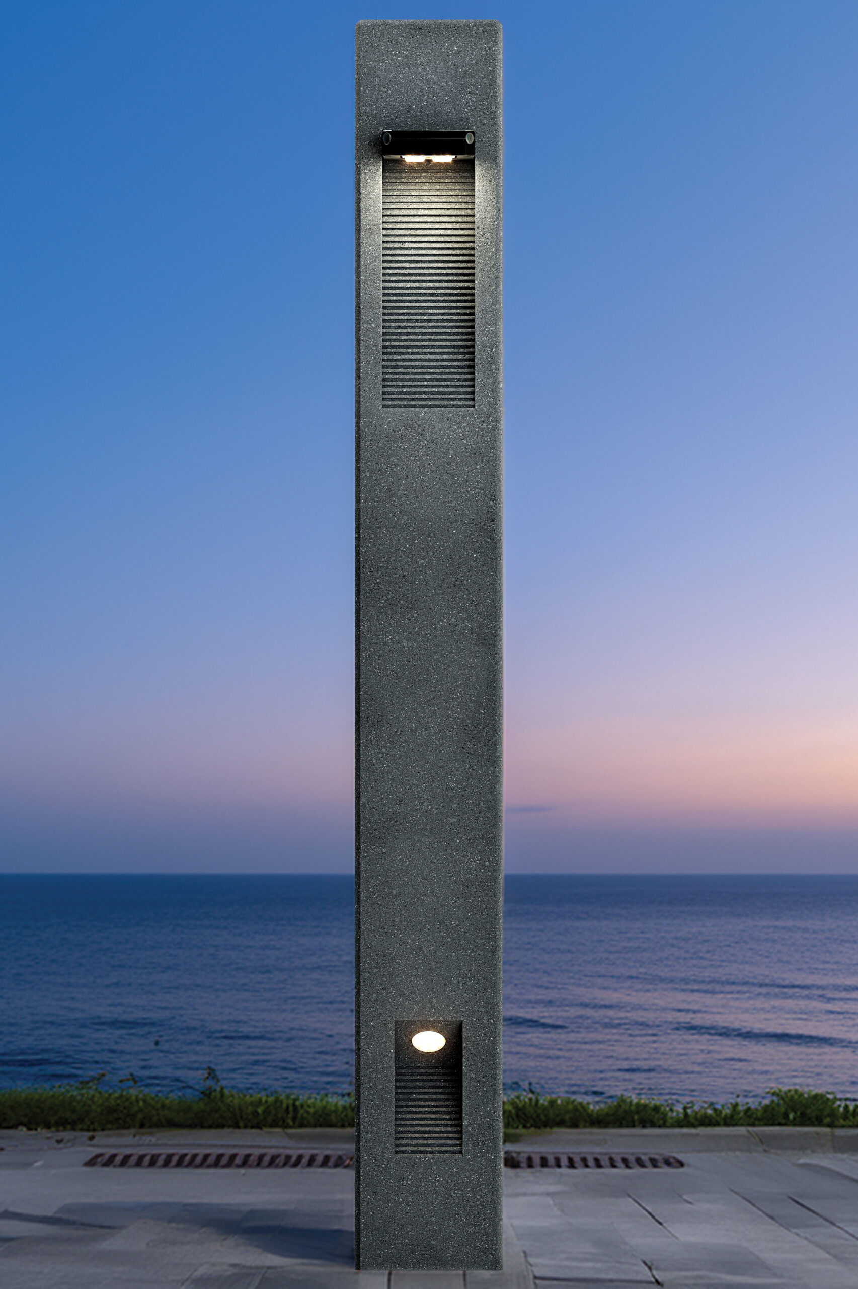 Architectural solar bollard light installed along a waterfront promenade providing sustainable pathway illumination.