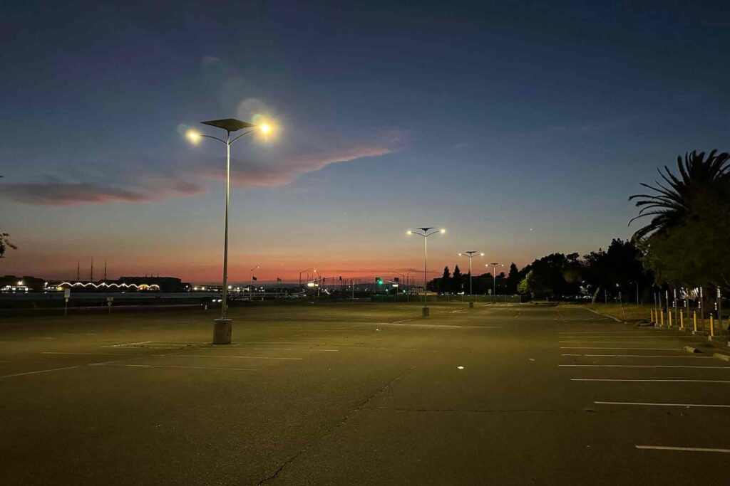 Solar-powered street lights illuminating a Georgia parking lot at sunset, showcasing off-grid, energy-efficient lighting solutions.
