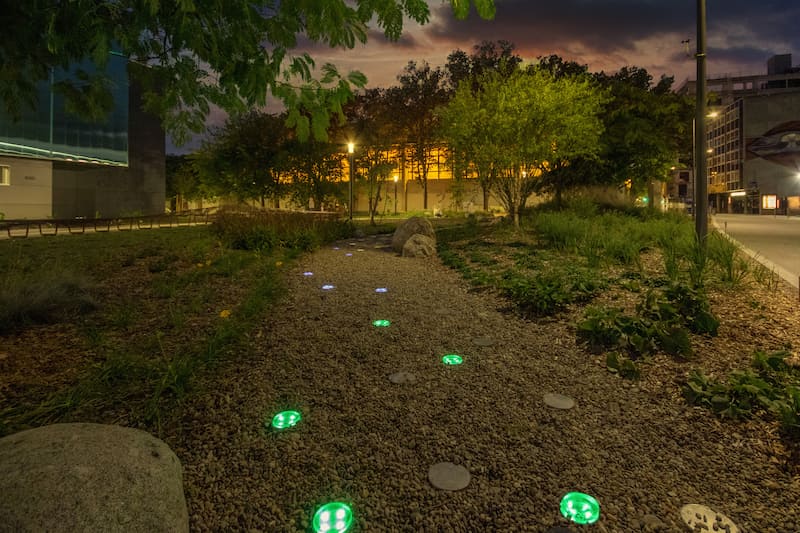Nowatt Crystal solar studs softly illuminating a gravel walkway at night, showcasing effortless Bluetooth-controlled, off-grid architectural lighting for parks, trails, and pedestrian pathways.