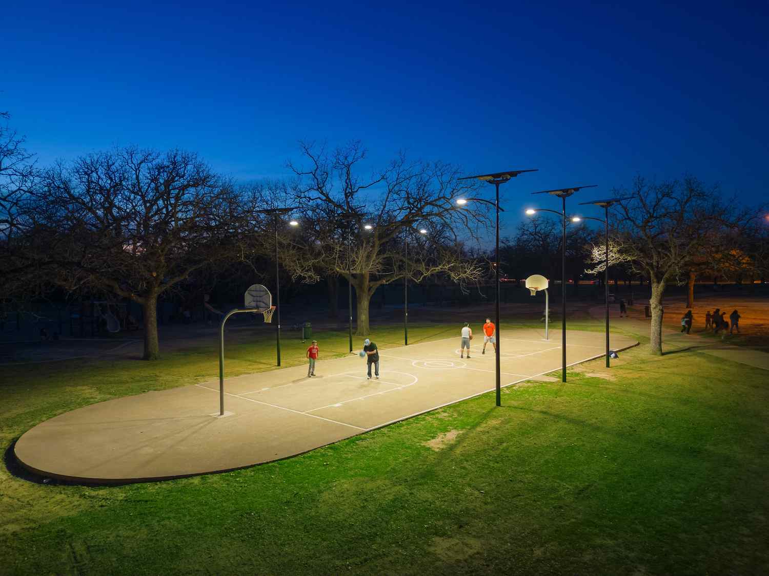 Community basketball court in South Carolina illuminated by solar-powered streetlights at dusk, providing safe and reliable lighting for parks and recreational spaces.