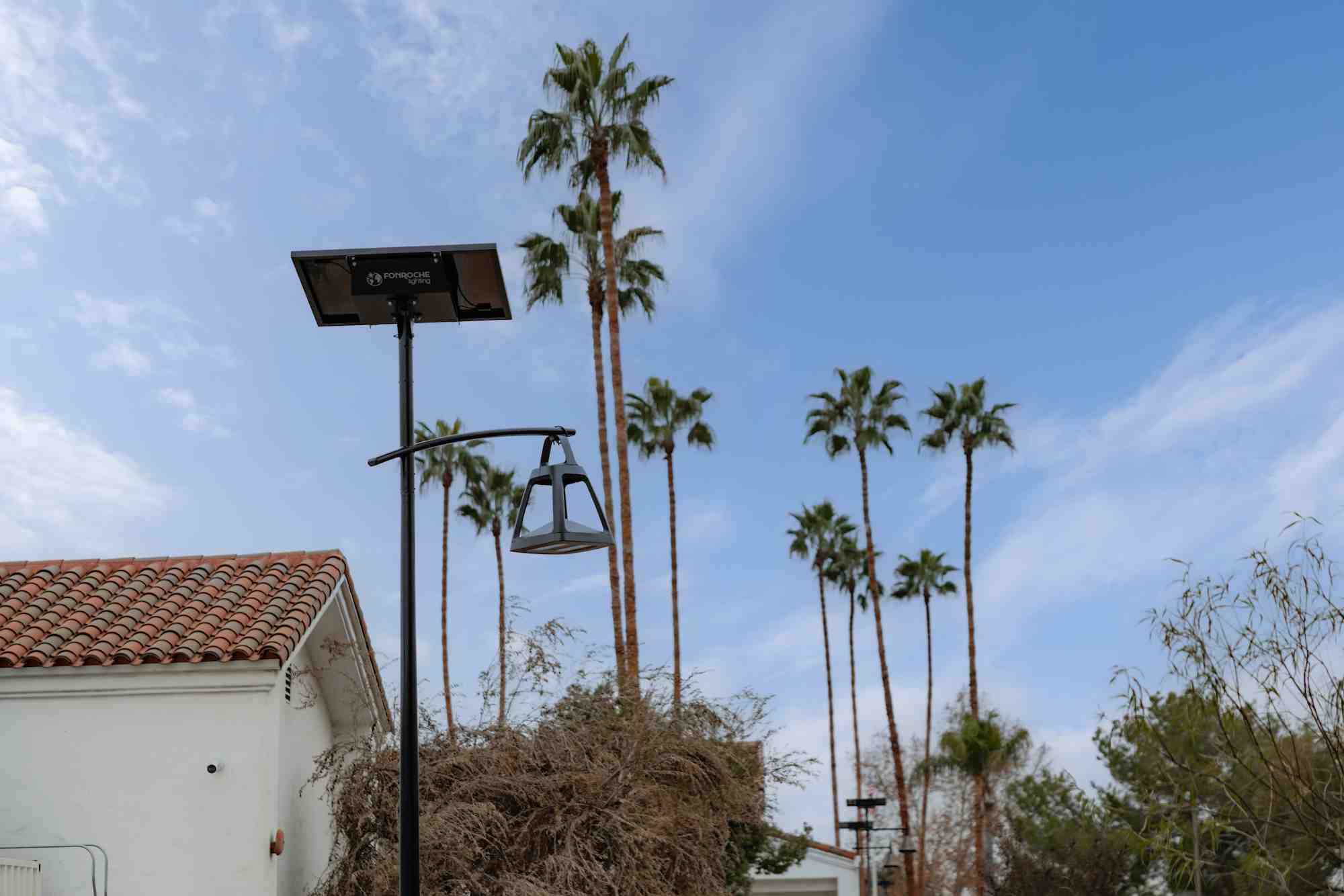 Fonroche solar-powered streetlight installed in a California community, with palm trees and Spanish-style architecture in the background.