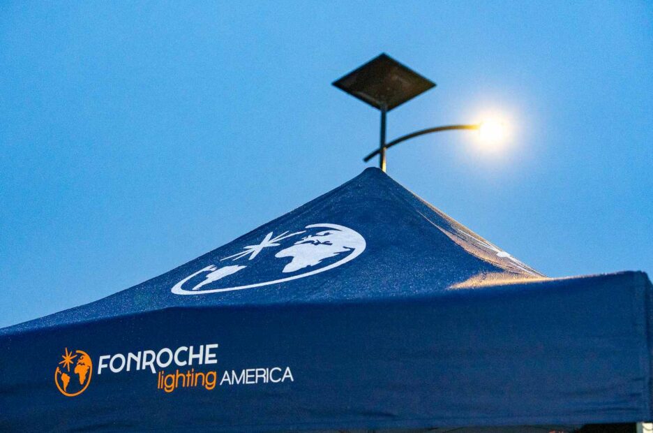 Fonroche Lighting America solar-powered streetlight illuminating at dusk with company canopy in foreground during Florida project event