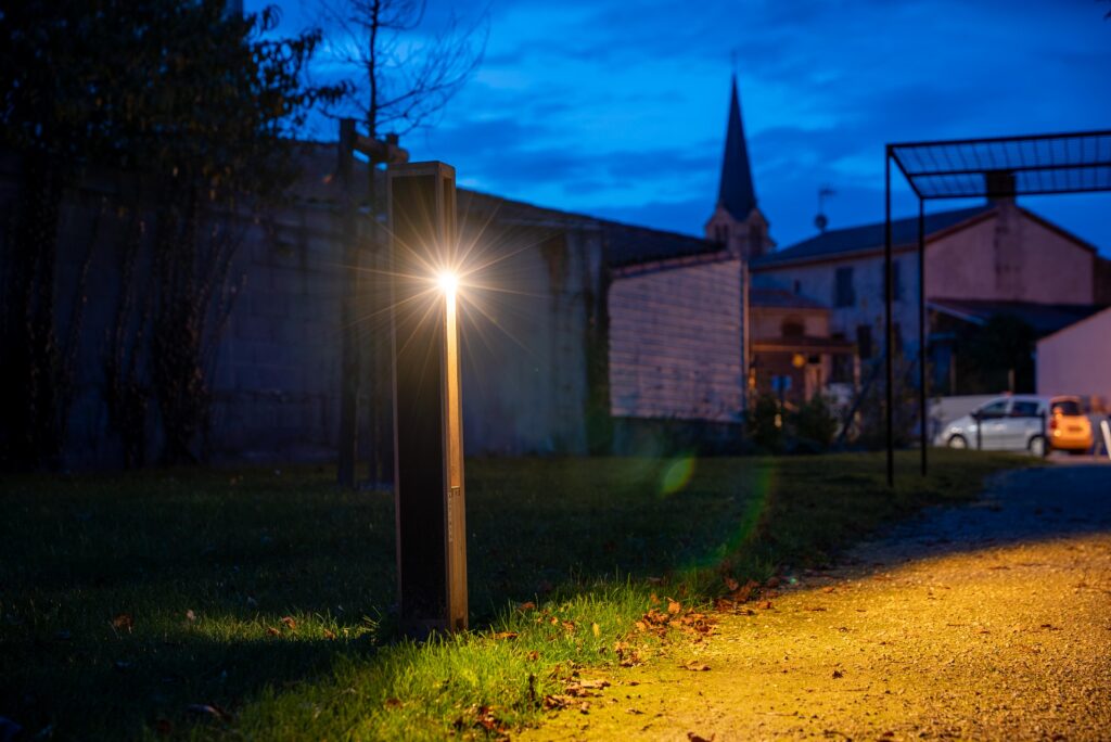 Illuminated solar bollard lighting a commercial lot at night with warm, uniform light—off-grid, low-glare, and dark-sky compliant.