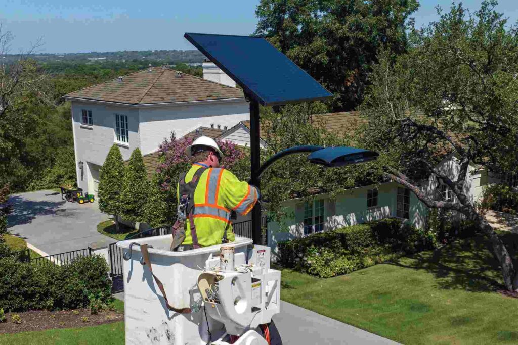 Installer setting up a Fonroche SmartLight solar streetlight in a parking lot for off-grid, maintenance-free lighting installation.