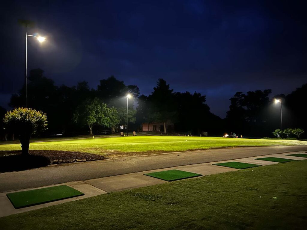 Solar-powered streetlights illuminate a grassy park trail at night, enhancing visibility and safety in a wooded Alabama greenway.