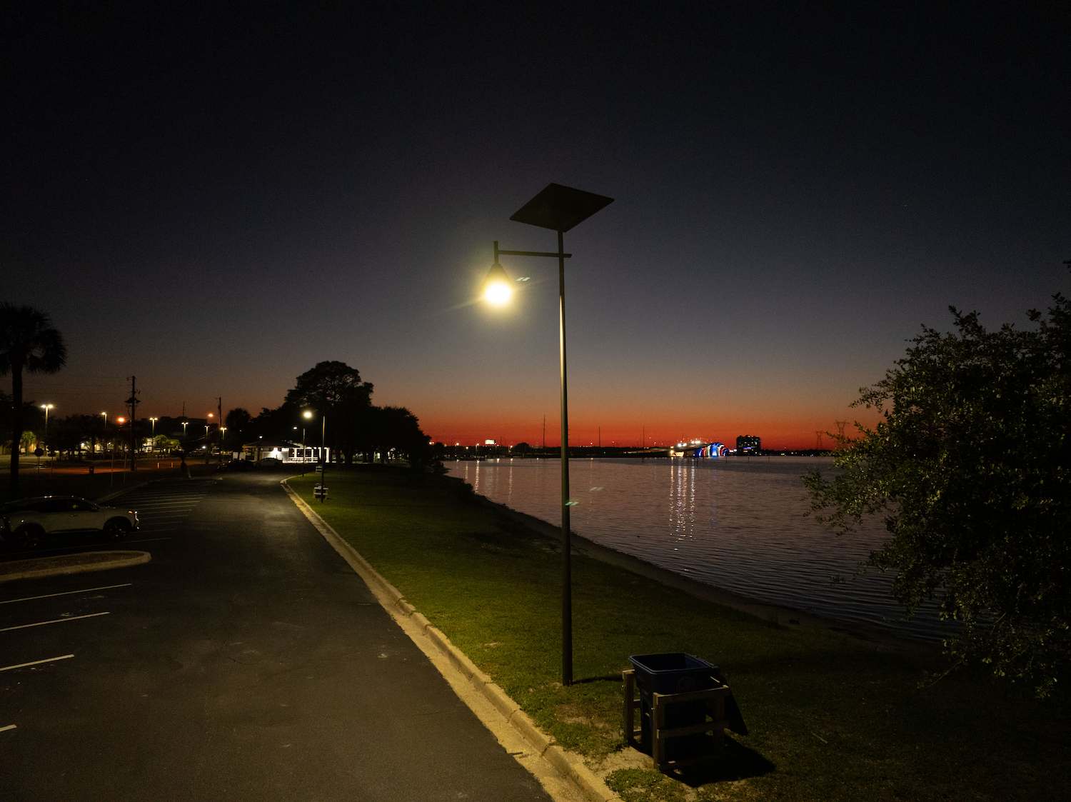 Solar street light illuminating a waterfront roadway and pedestrian path at night in Florida