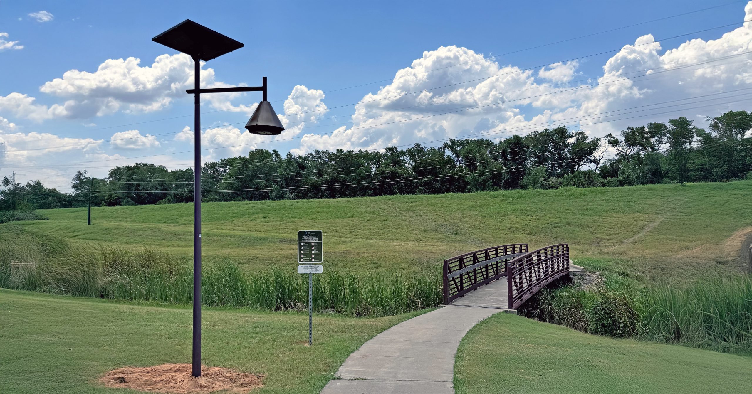 opera-solar-lighting-park-trail-pedestrian-bridge.jpg Belle Époque solar street light illuminating a pedestrian pathway and bridge in a park setting.