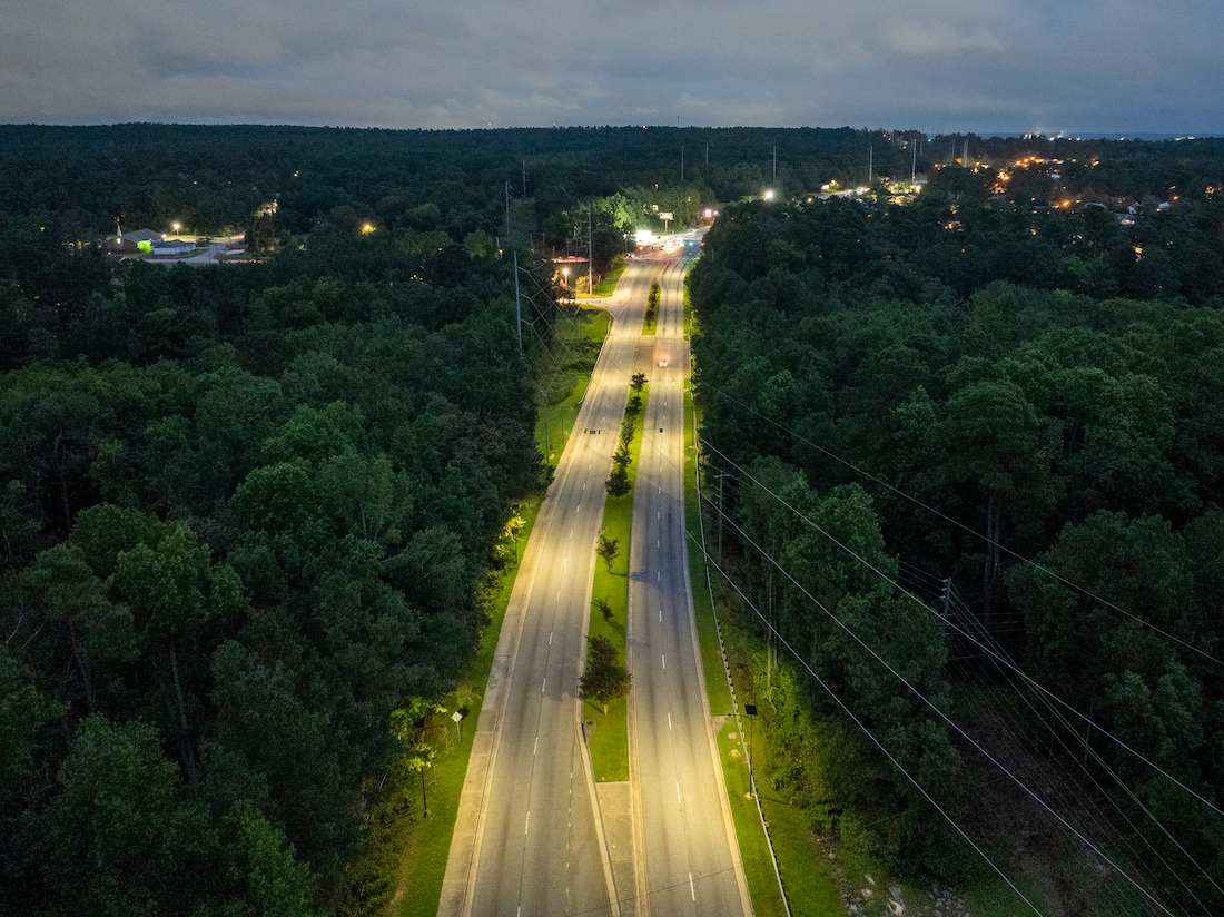 Aerial view of a roadway illuminated by solar street lights at night, improving visibility and roadway safety for municipal streets and public infrastructure.