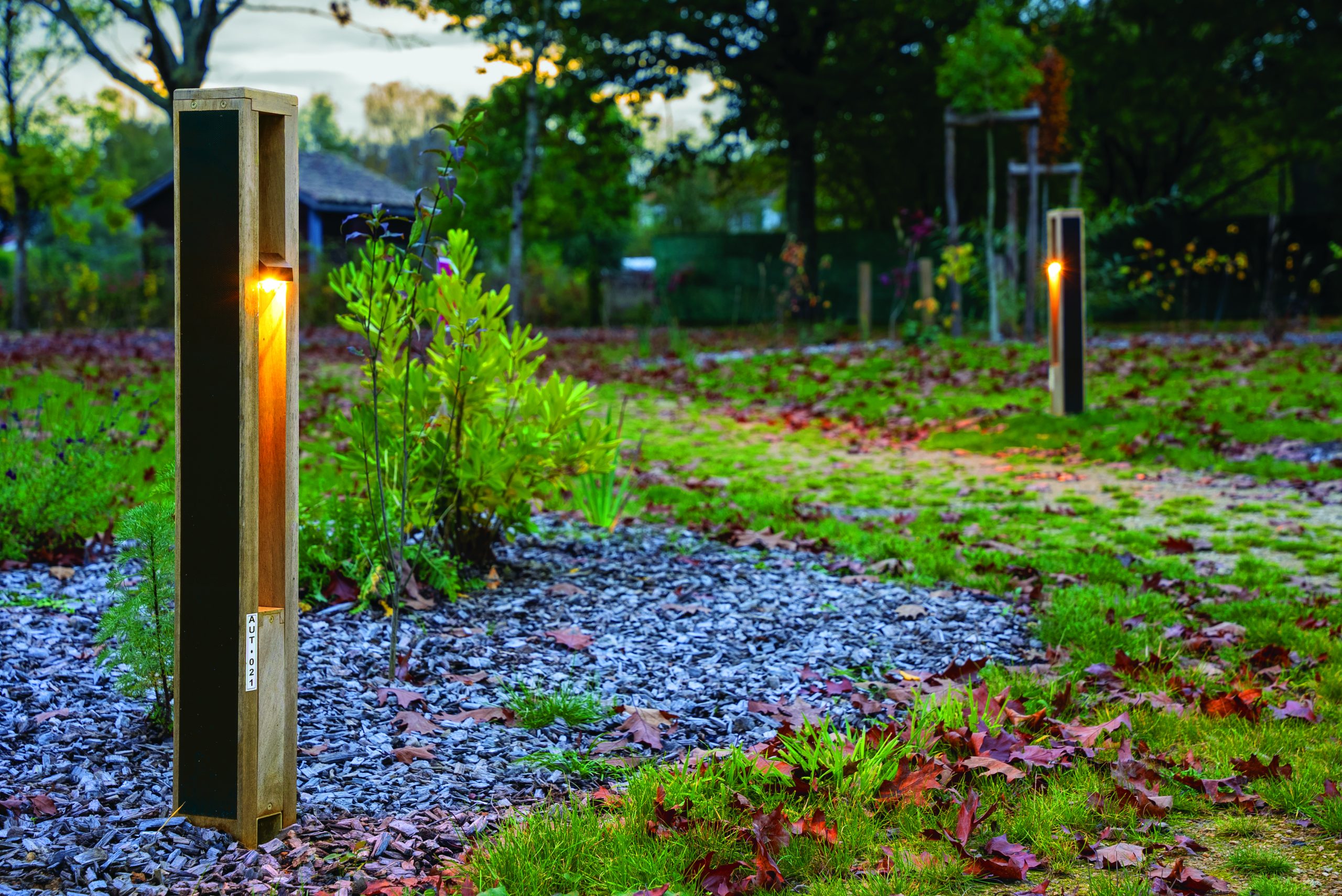 oko-solar-bollard-pathway OKO solar bollard light illuminating a landscaped pathway with compact off-grid lighting in a modern outdoor environment.