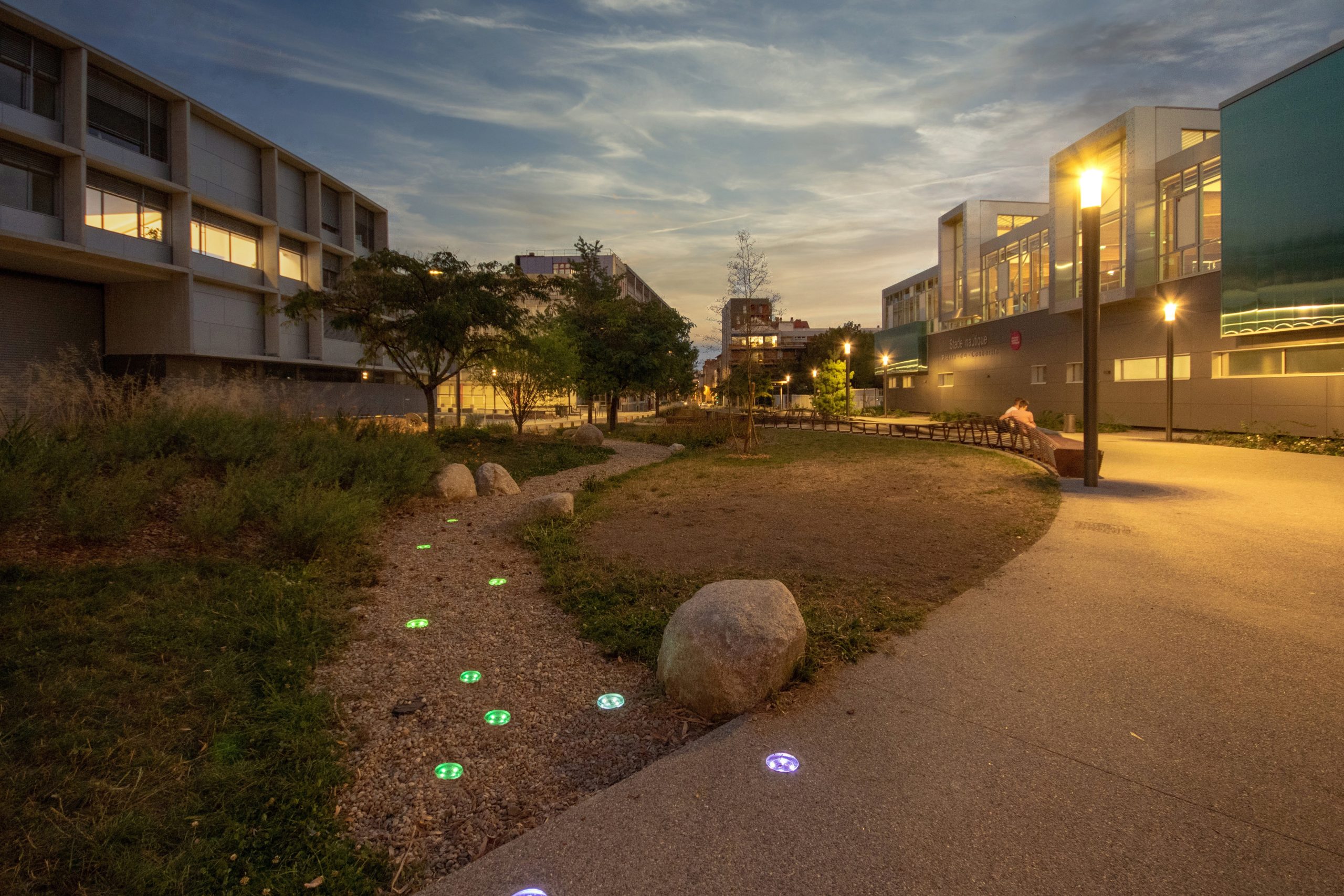 solar-crystal-stud-lights-urban-pathway-dusk-landscape-lighting.jpg Solar-powered CRYSTAL STUD pathway lights embedded along a pedestrian walkway beside a modern residential and commercial development at dusk.