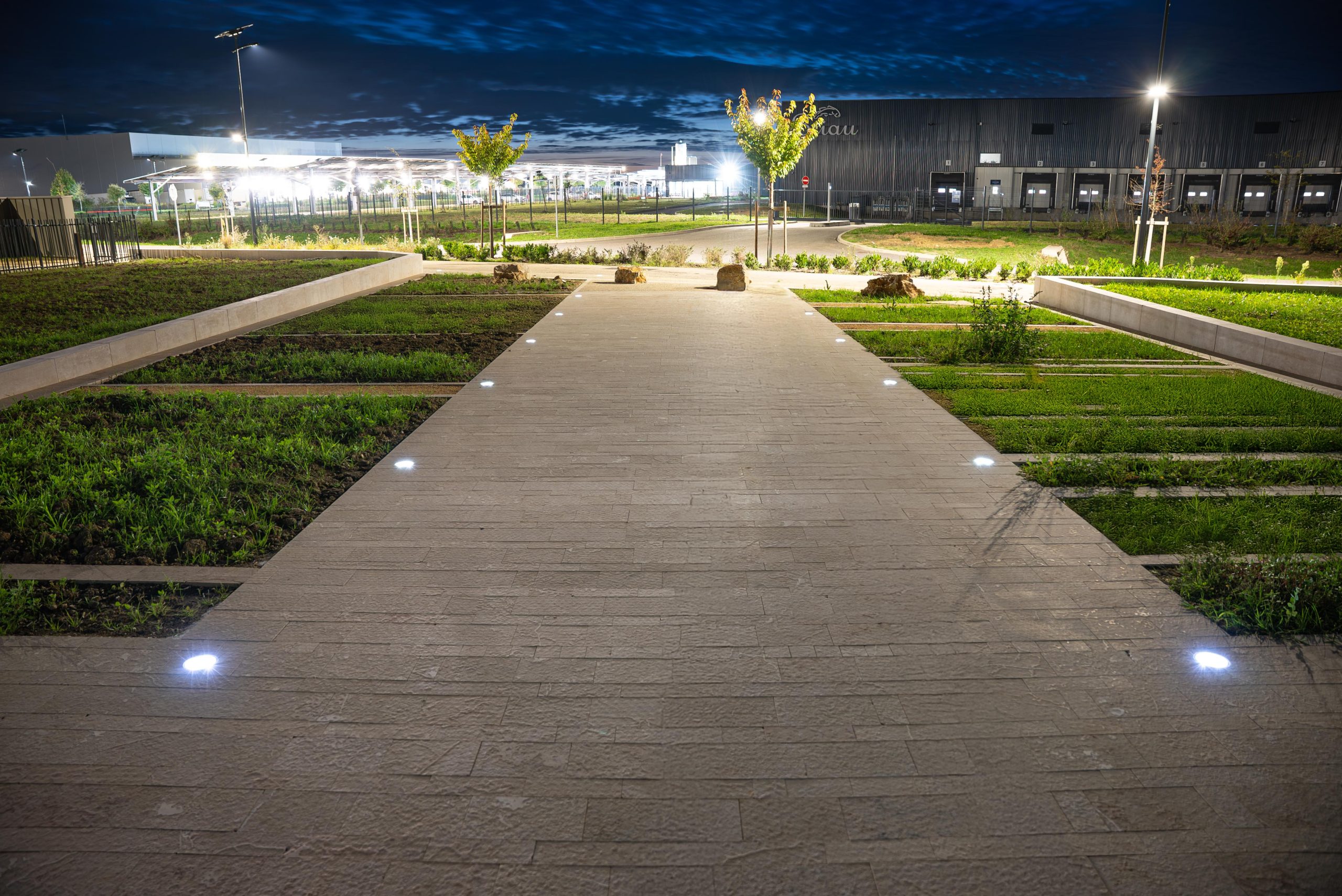solar-landscape-lighting-pathway-commercial-outdoor-night.jpg Illuminated pedestrian walkway featuring solar crystal studs embedded in the pathway for safe nighttime guidance in public outdoor spaces.
