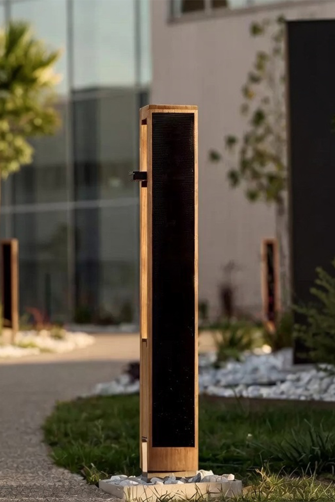 Architectural solar bollard light installed along a landscaped pedestrian pathway in a commercial outdoor space.