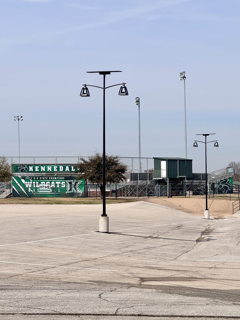 Solar-powered pathway lighting installed at a high school campus entrance with off-grid bollard lights illuminating sidewalks, student walkways, and school grounds.