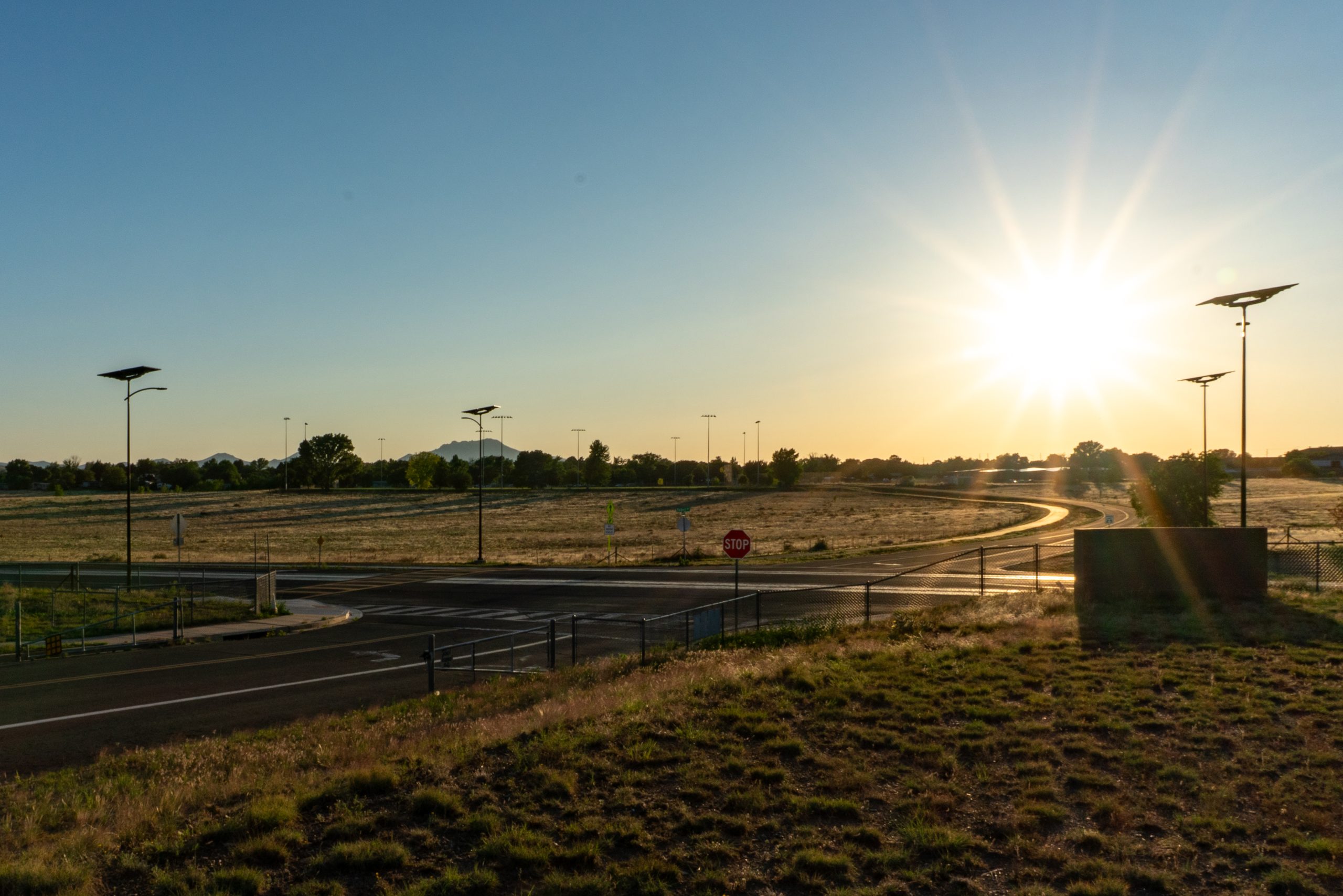 solar-roadway-lighting-intersection-sunrise.jpg Solar-powered street lights illuminating access roads and transportation routes at sunset with resilient off-grid lighting for military and federal facilities.