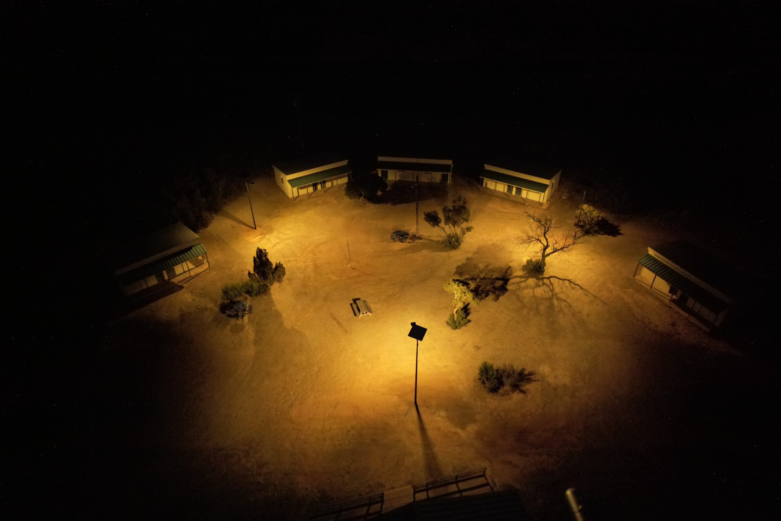 essential-smartlights-military-dormitory-space Aerial nighttime view of solar-powered lighting illuminating military training grounds and tactical zones with reliable off-grid security lighting.