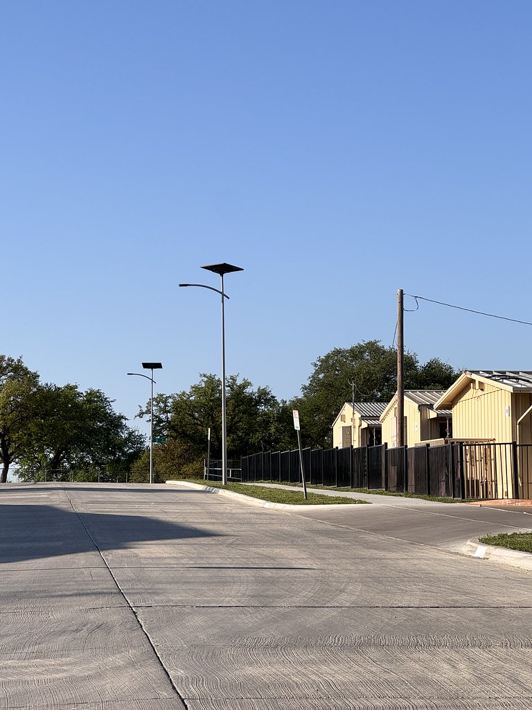 essential-smartlights-military-parking-area Solar-powered street lights illuminating a large parking lot and motor pool area at dusk, providing reliable off-grid lighting for federal and military facilities.