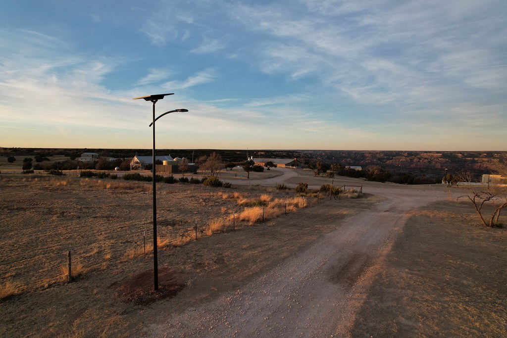 Solar-powered pathway lighting illuminating a residential pedestrian walkway surrounded by trees, providing safe and sustainable lighting for tribal communities.