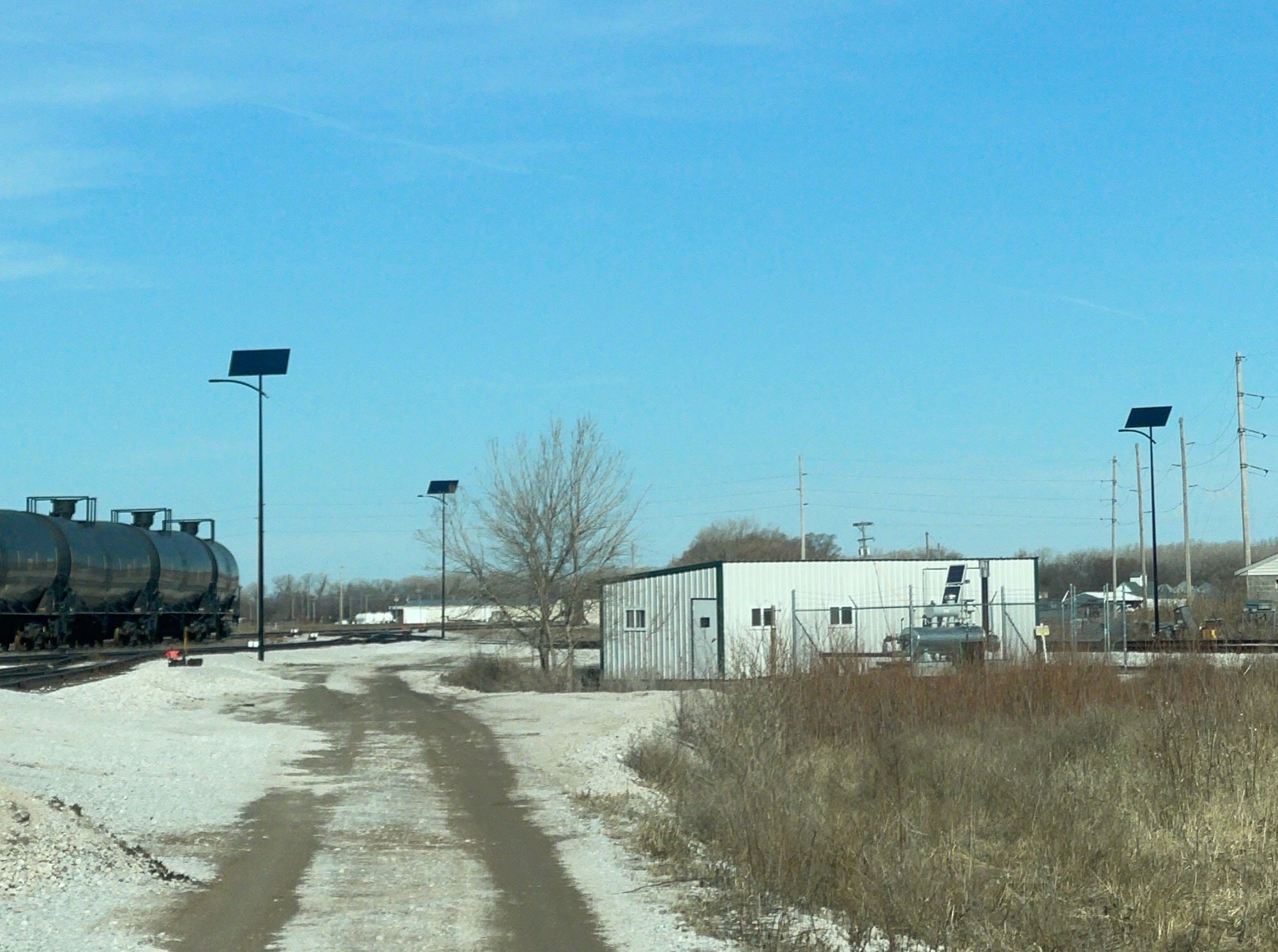Solar-powered street light illuminating an industrial utility yard and secure service area at dusk with reliable off-grid exterior lighting.