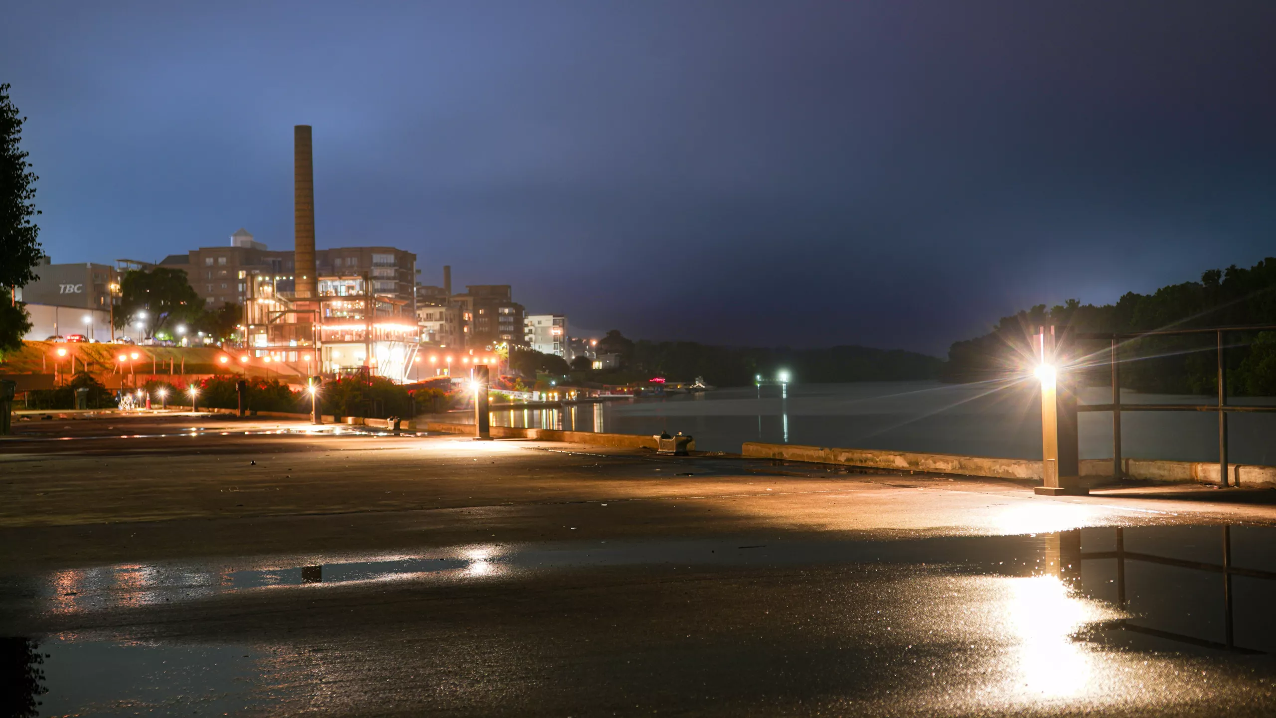 Solar LED bollard lights illuminating a waterfront promenade at night, providing safe and energy-efficient pedestrian lighting along the riverfront.