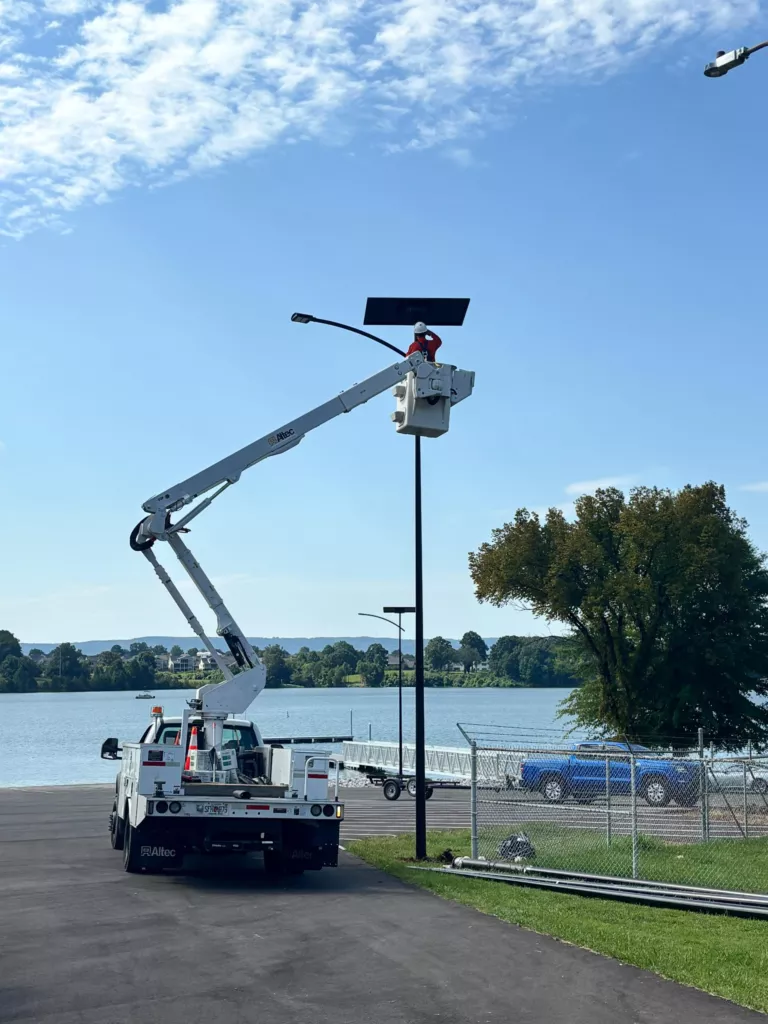 Crew installing an autonomous solar streetlight using a bucket truck