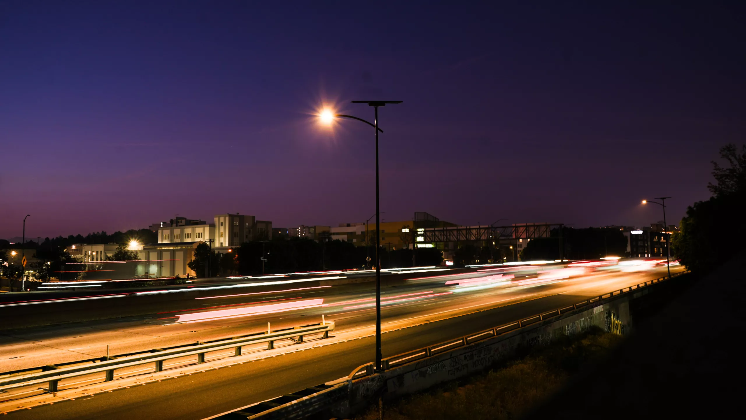 olar streetlights illuminating a busy roadway at dusk.